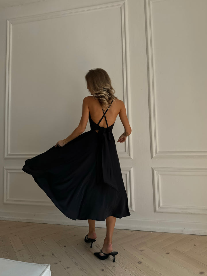 Black silk slip midi dress with deep V-neck and open bow back — front view