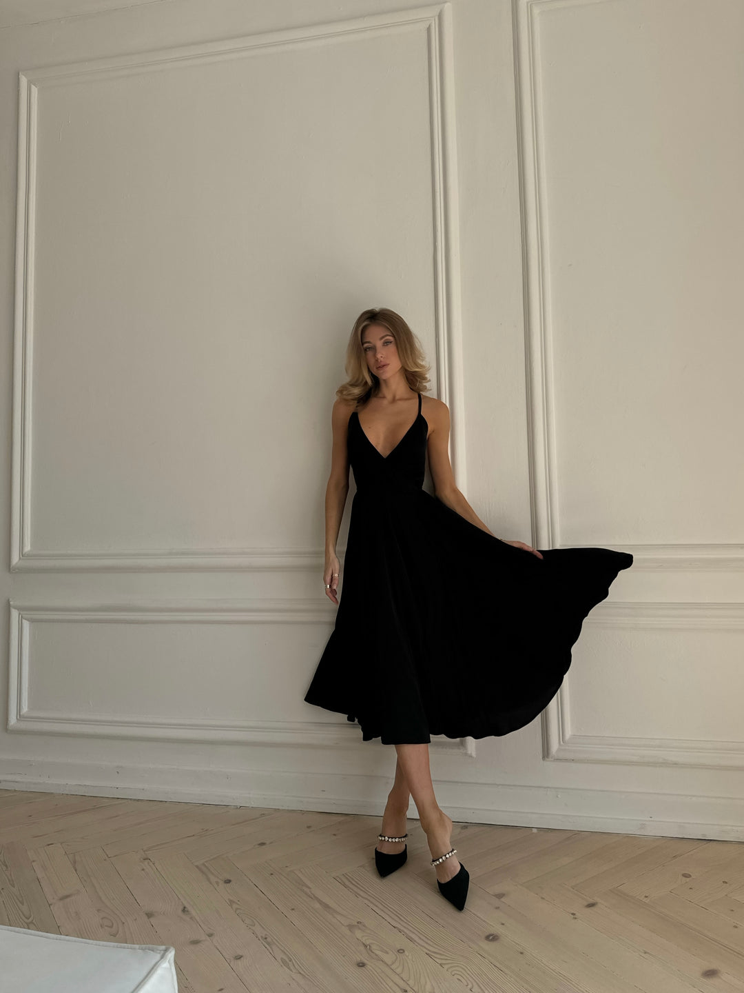 Back view of black silk midi dress showing open back and bow tie closure