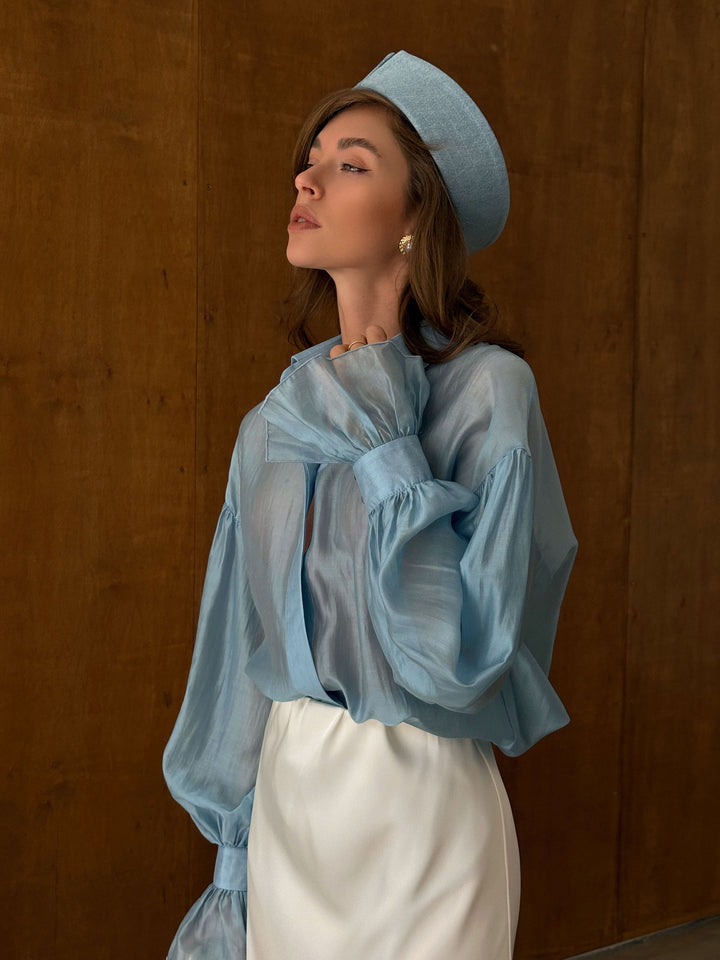 Side profile of the ice blue sheer blouse showing straight hemline and airy sleeve volume