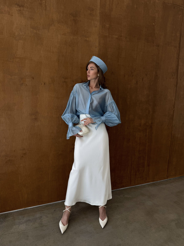 Full-length outfit shot of ice blue sheer blouse styled with ivory satin midi skirt