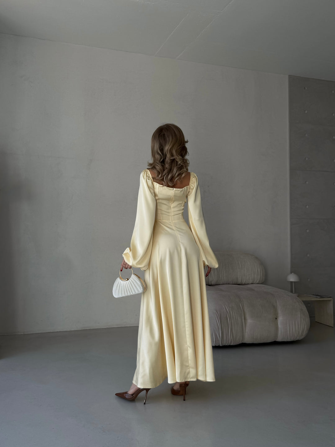 Butter yellow long-sleeve evening gown made of smooth satin. Features a structured sweetheart neckline and high side slit, ideal for a formal event or upscale dinner.