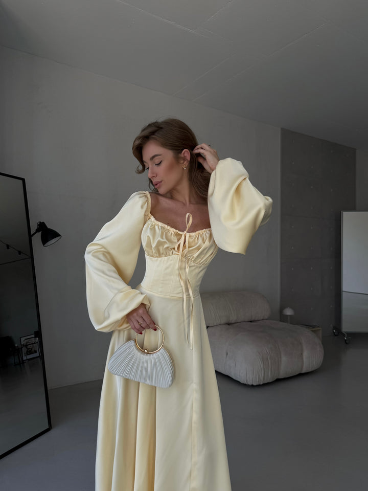 Floor-length satin maxi dress in butter yellow with a flattering sweetheart neckline and versatile draped sleeves. A refined option for a stylish date night outfit.