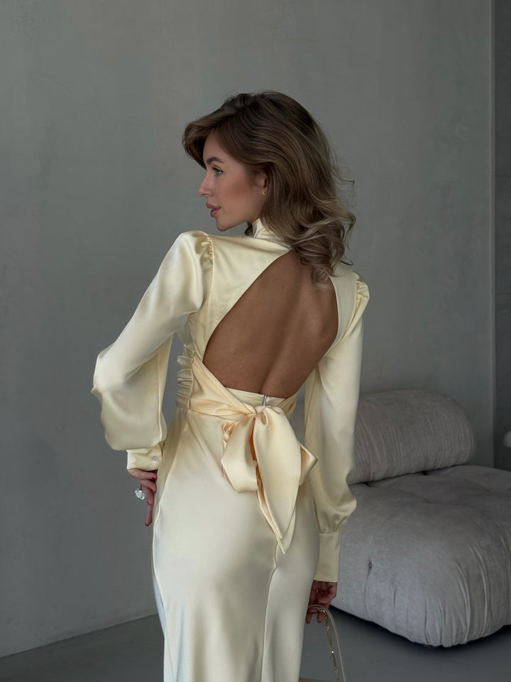 back view of a butter yellow silk midi dress showing an alluring open back and adjustable bow tie closure