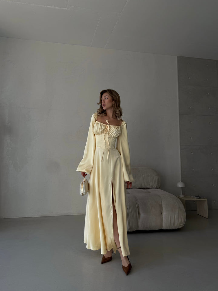 Premium butter yellow silk-like maxi gown featuring delicate draped sleeves, a sweetheart neckline, and a leg slit. An elegant outfit for a destination vacation.