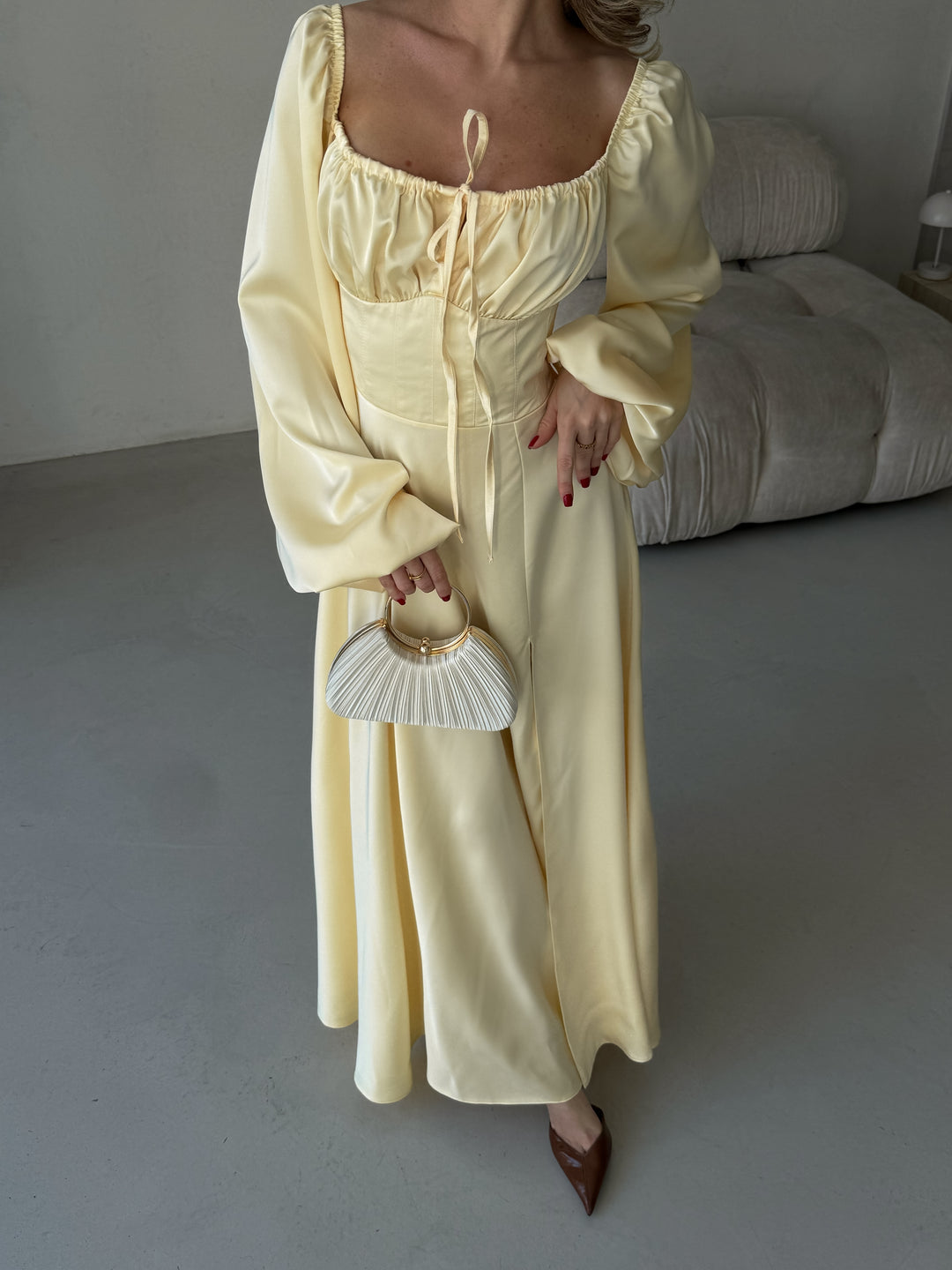 Pastel yellow long-sleeve formal maxi dress made from silky satin. Features an elegant high leg slit and sweetheart bust, perfect for a chic summer wedding guest.