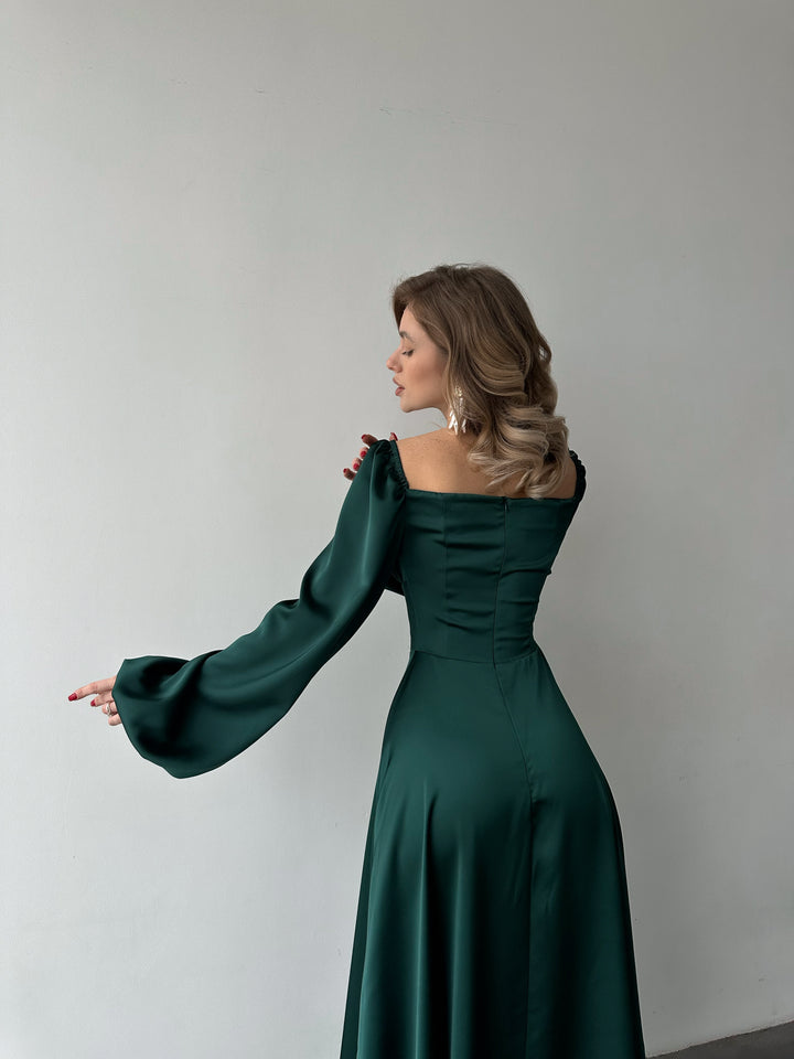 Flowing dark green satin gown with off-the-shoulder balloon sleeves and a high slit. A modern modest option for a chic holiday party outfit.