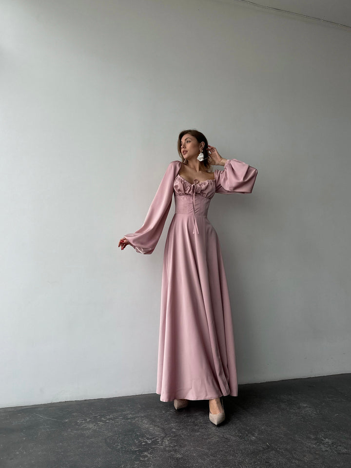 Pastel light pink long-sleeve evening dress made of smooth satin. Features a structured sweetheart bust and side slit, ideal for a formal event.
