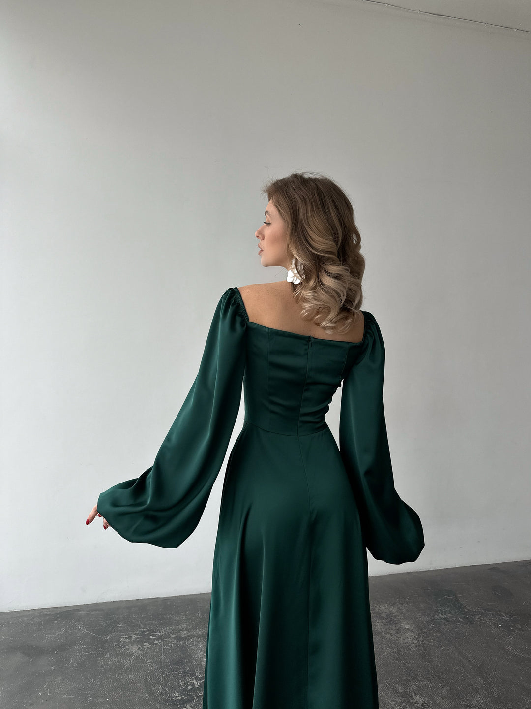 Jewel-toned green long-sleeve evening dress made of smooth satin. Features a structured sweetheart bust and side slit, ideal for a formal gala.