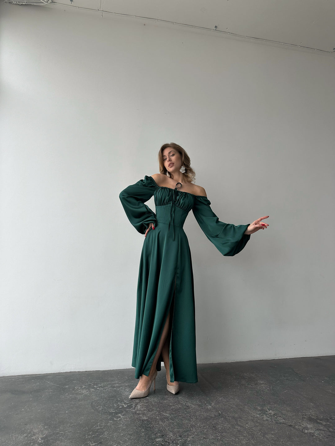 Sophisticated green satin dress offering long cuffed sleeves and a high slit maxi skirt. Perfect for a chic winter wedding guest appearance.