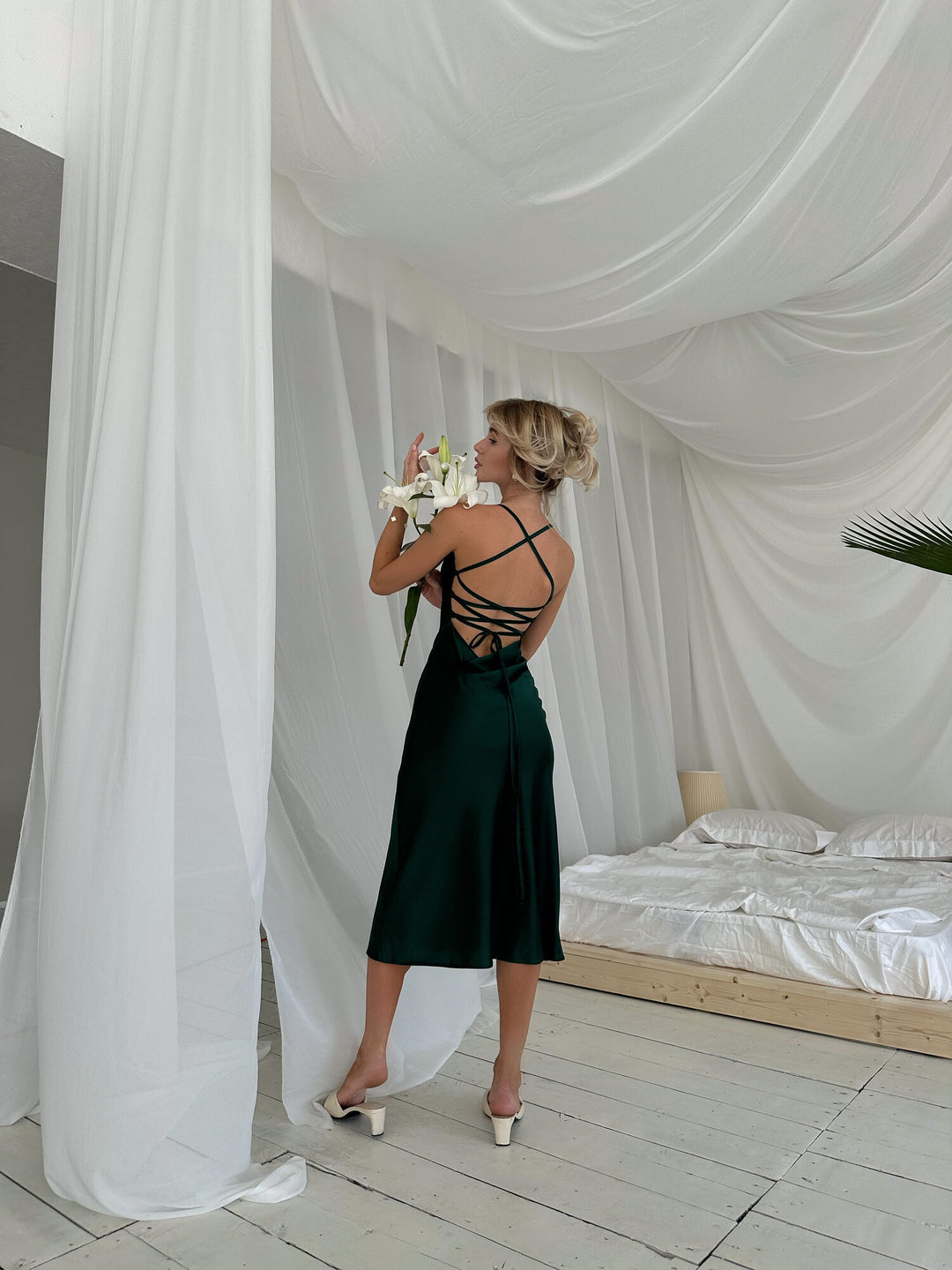 Full length back view of emerald green satin slip dress with lace-up open cross-back. Spaghetti straps