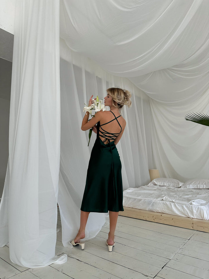 Full length back view of emerald green satin slip dress with lace-up open cross-back. Spaghetti straps