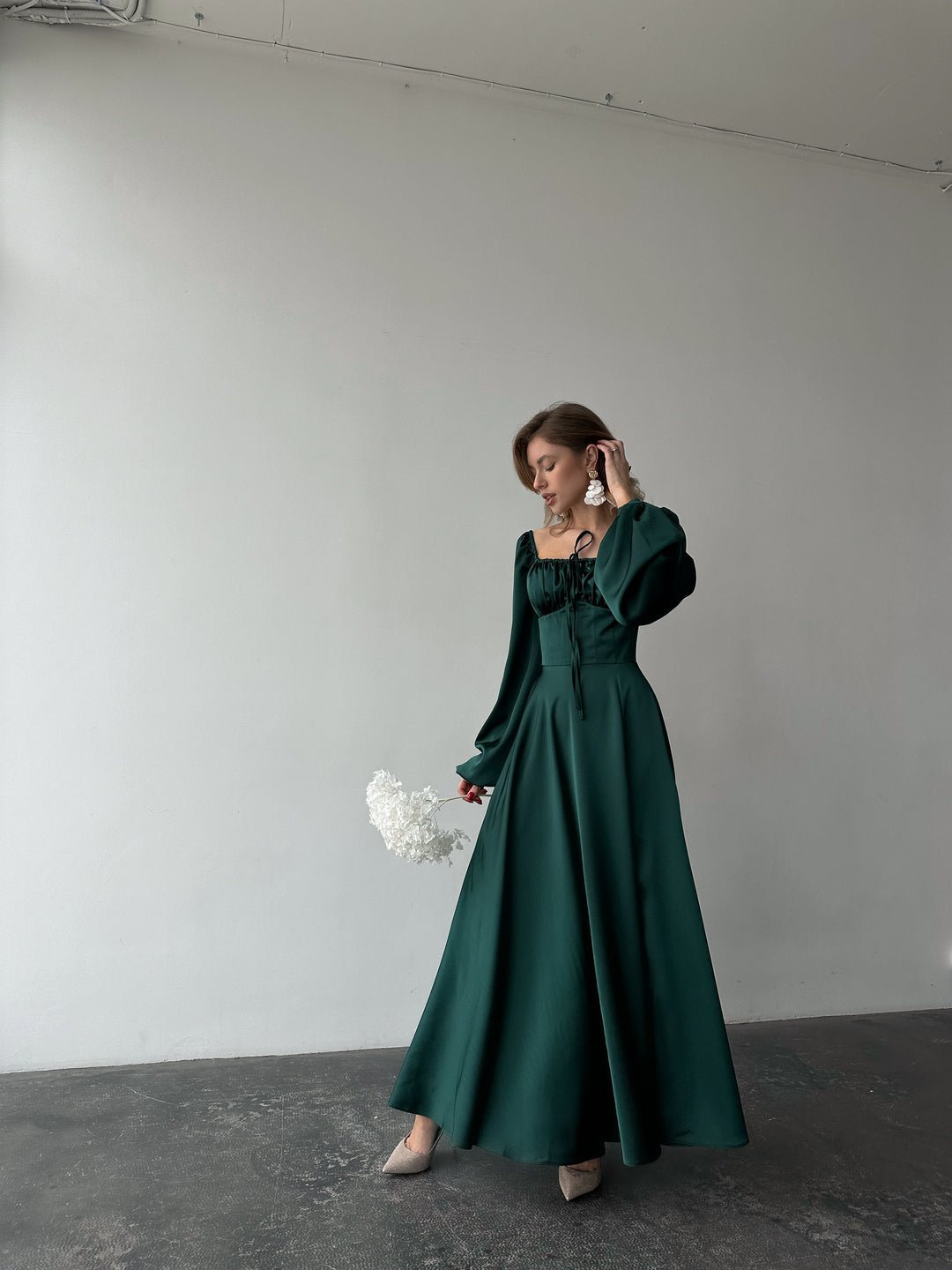 Beautifully draped emerald green silk dress featuring a feminine sweetheart neckline and long balloon sleeves. A luxurious formal party outfit.