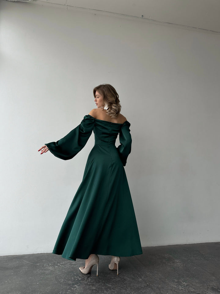 Premium emerald green silk-like maxi dress featuring delicate draped sleeves and a leg slit. An elegant outfit choice for an upscale evening out.