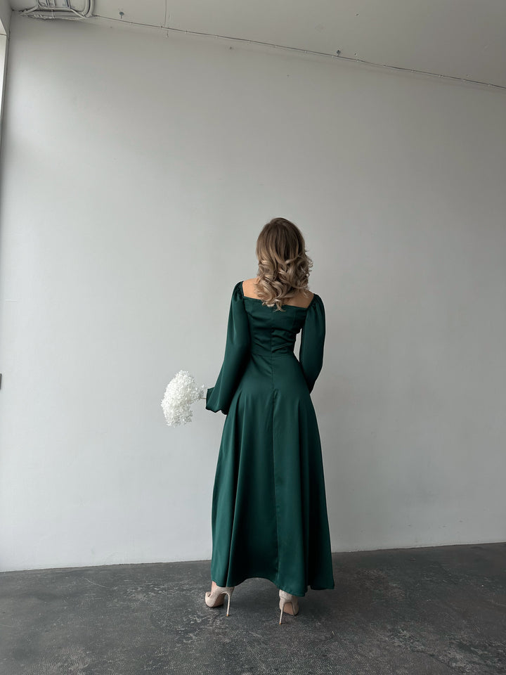 Vibrant emerald green silk maxi gown featuring a corset-inspired bodice, long balloon sleeves, and a high slit. A chic NYC style outfit for a black-tie formal event.
