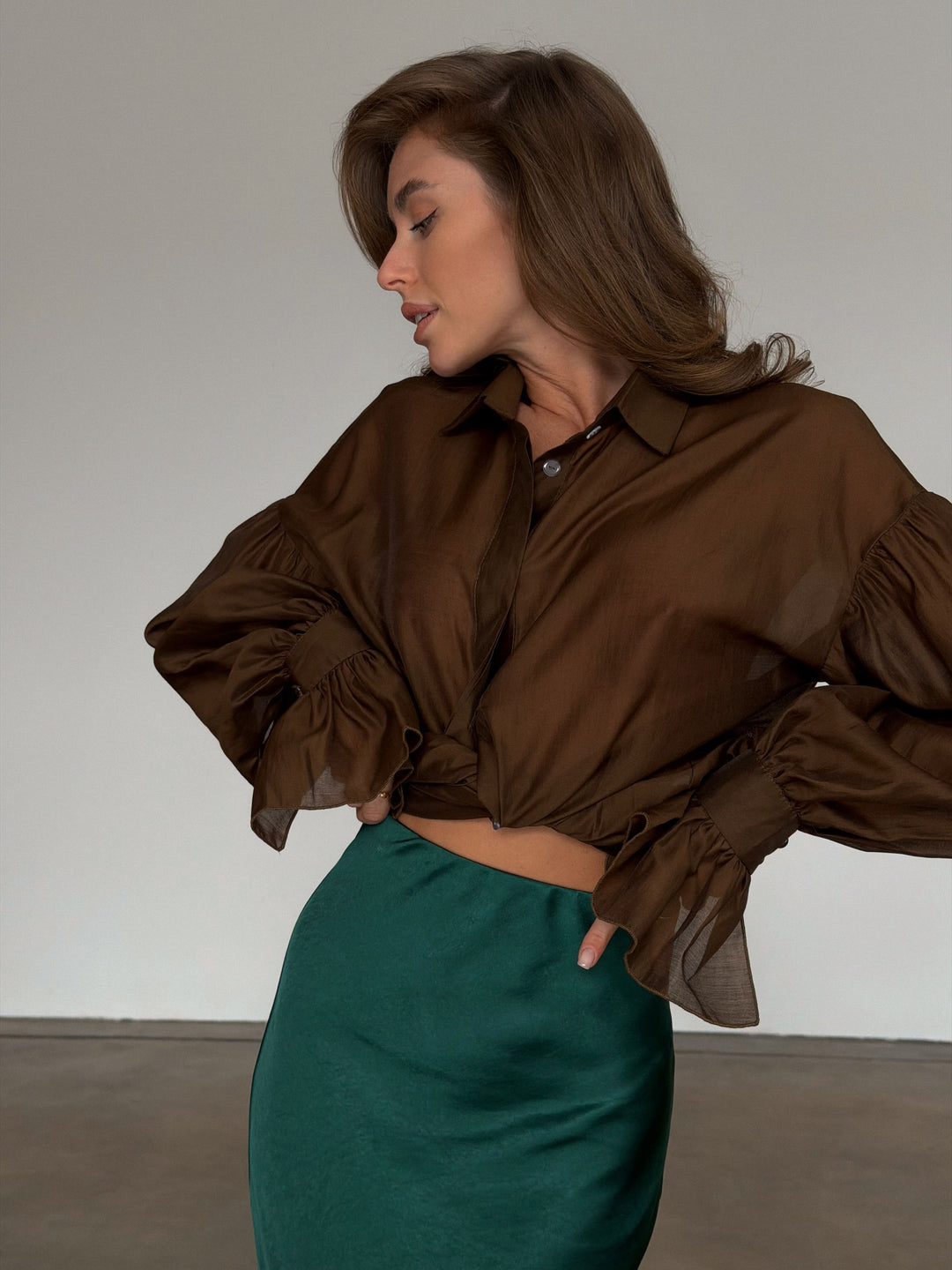 Close detail of the clean, seamless waistline construction on the dark green slip skirt.