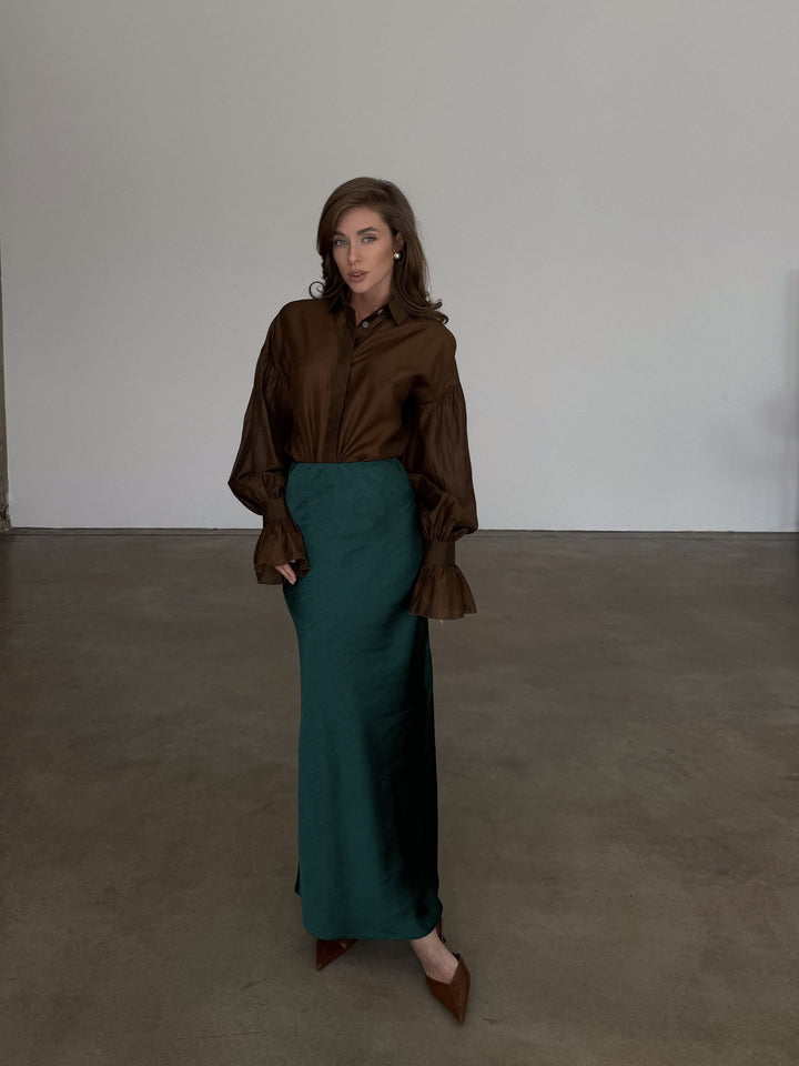 Detailed front angle highlighting the smooth, tailored fit over the hips of the dark emerald skirt.