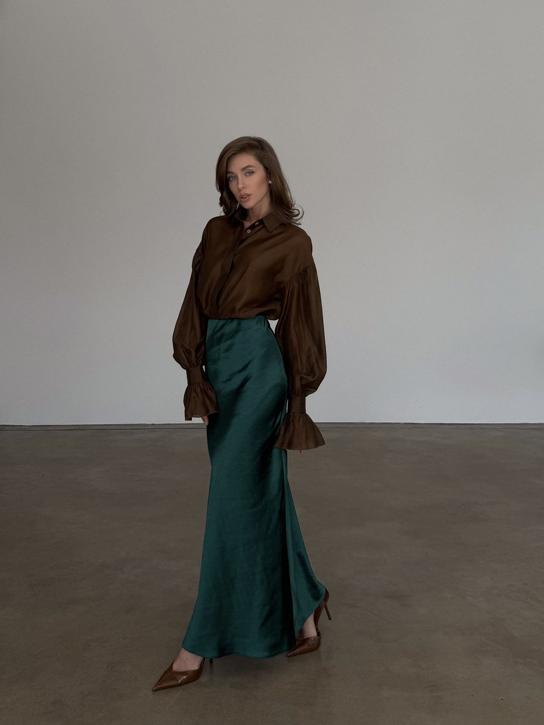 Side view showing the seamless design of the dark emerald satin skirt.