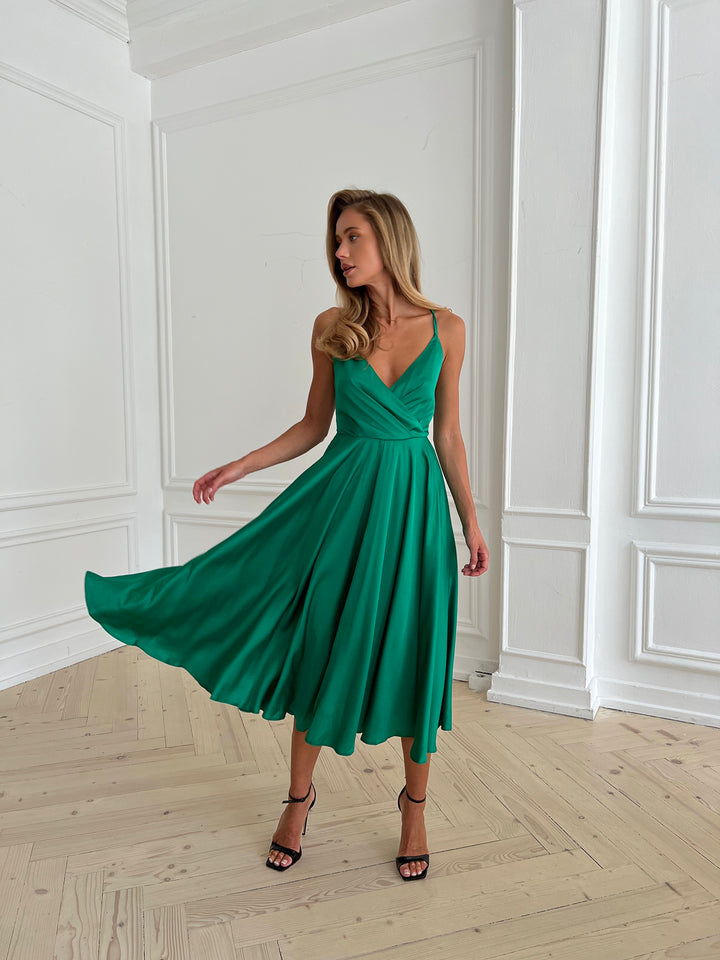 Woman wearing grass green silk midi dress as bridesmaid at garden wedding