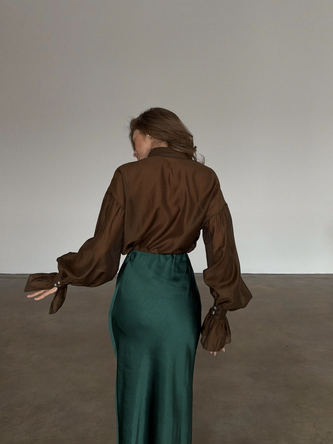 Rear mid-section view highlighting how the bias-cut green fabric contours softly over the back and hips.