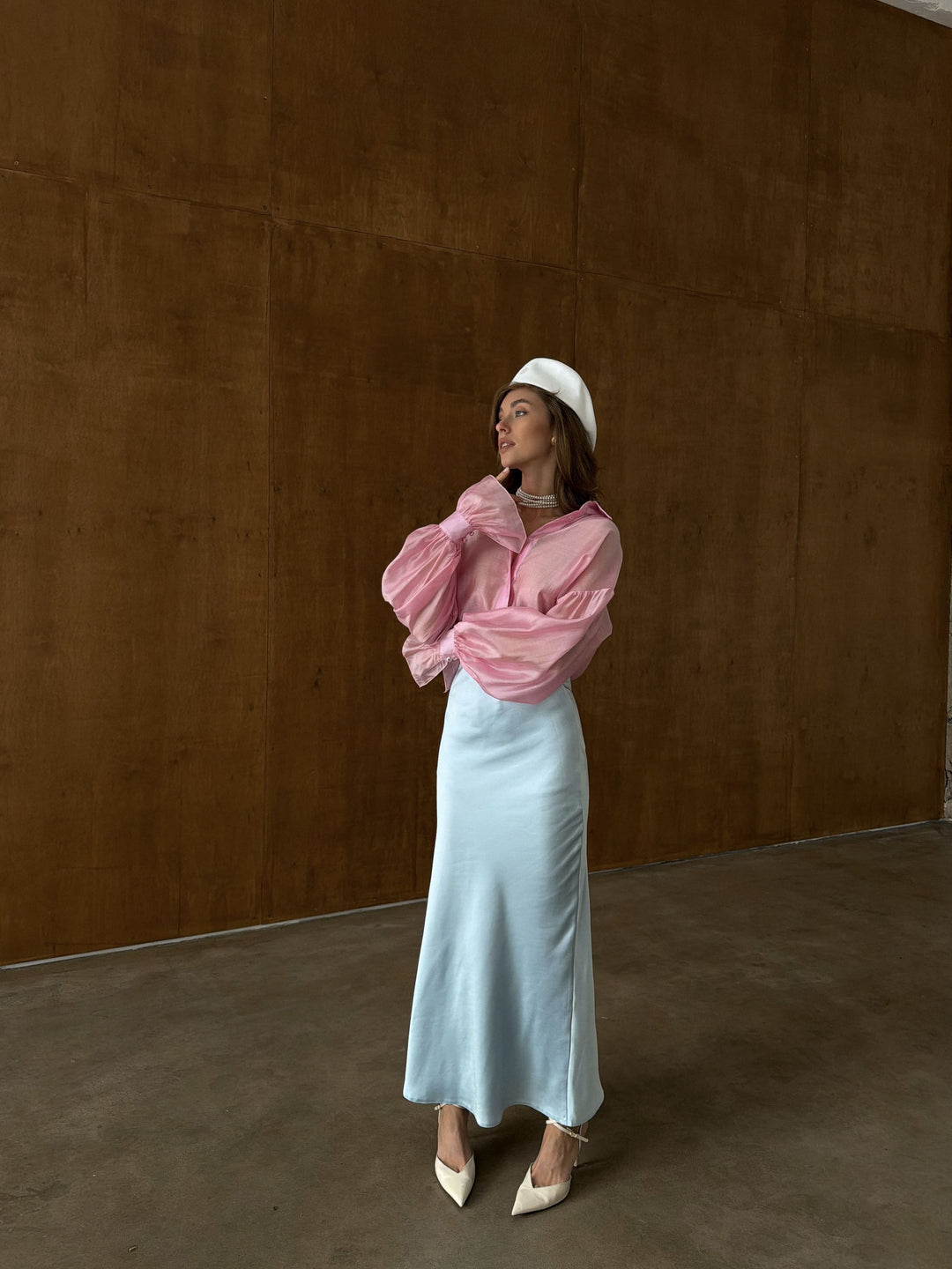 Front view of ice blue satin midi skirt on model in a studio setting, showing the elastic waistband, smooth A-line drape, and ankle-length hemline