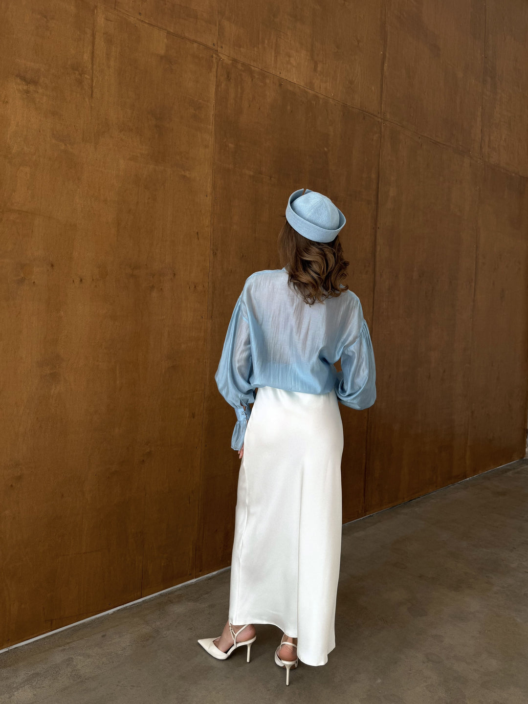 Back view of the ivory satin skirt with a fitted waist and flowing hemline.