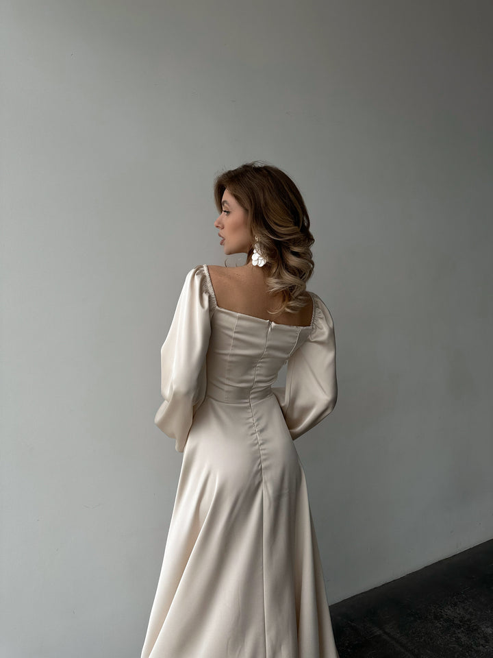 Ivory silk satin maxi dress three-quarter back view — bishop sleeves off the shoulder, high leg slit, romantic silhouette. Perfect for elopements, bridal shoots, wedding receptions, and black-tie evenings.