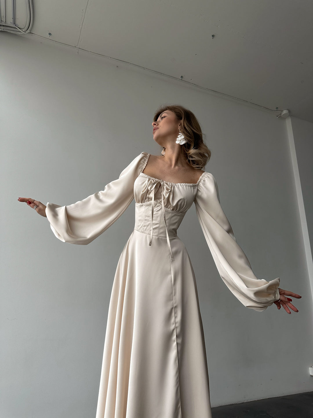 Ivory silk satin maxi dress — bishop sleeves spread wide showing full volume, lace-up corset front. Dramatic bridal silhouette. Perfect for editorial shoots, elopements, civil weddings, and gala evenings.