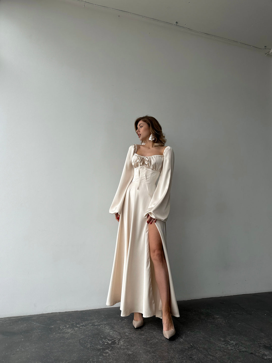 Ivory silk satin maxi dress with high leg slit in motion — bishop sleeves, sweetheart neckline, floor-length flowing skirt. Perfect for bridal wear, elopements, wedding receptions, and formal evening events.