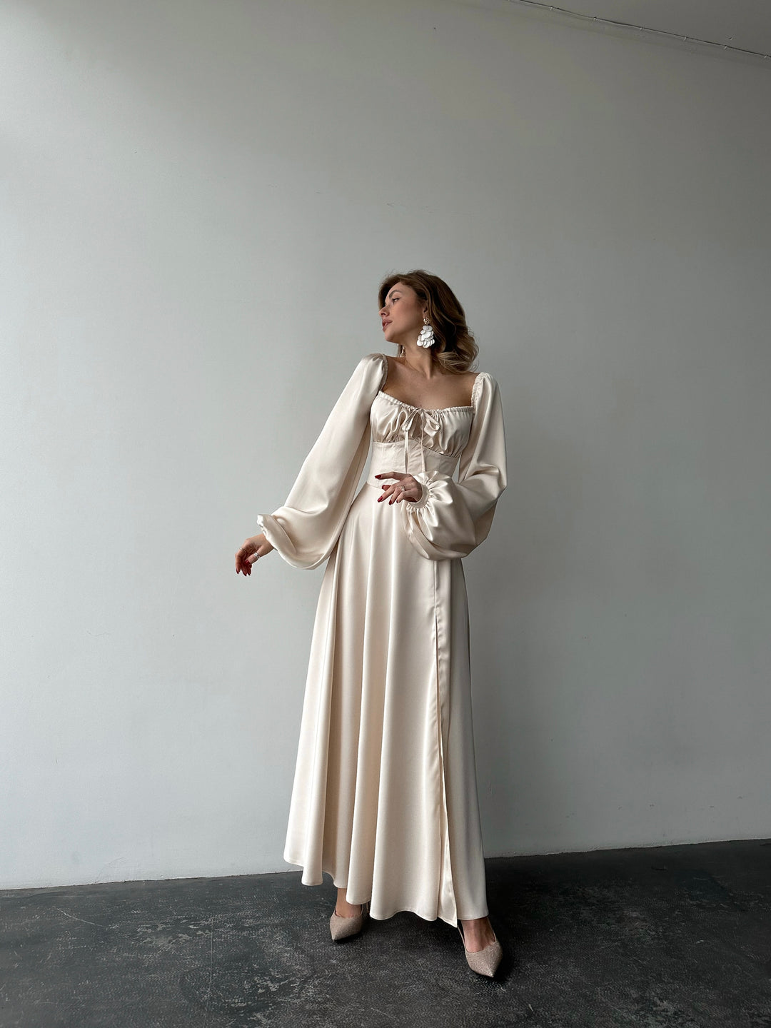 Ivory silk satin maxi dress full-length front view — bishop sleeves worn off the shoulder, floor-sweeping skirt with high slit. Luxurious drape. Perfect for wedding guests, elopements, rehearsal dinners, and formal evenings.