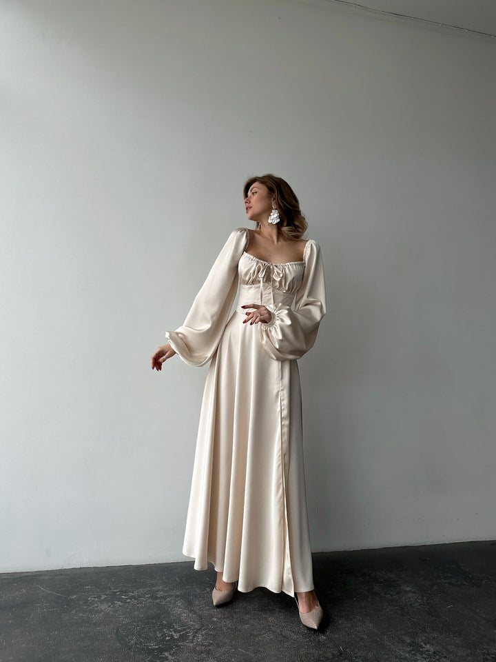 Ivory silk satin maxi dress full-length front view — bishop sleeves worn off the shoulder, floor-sweeping skirt with high slit. Luxurious drape. Perfect for wedding guests, elopements, rehearsal dinners, and formal evenings.