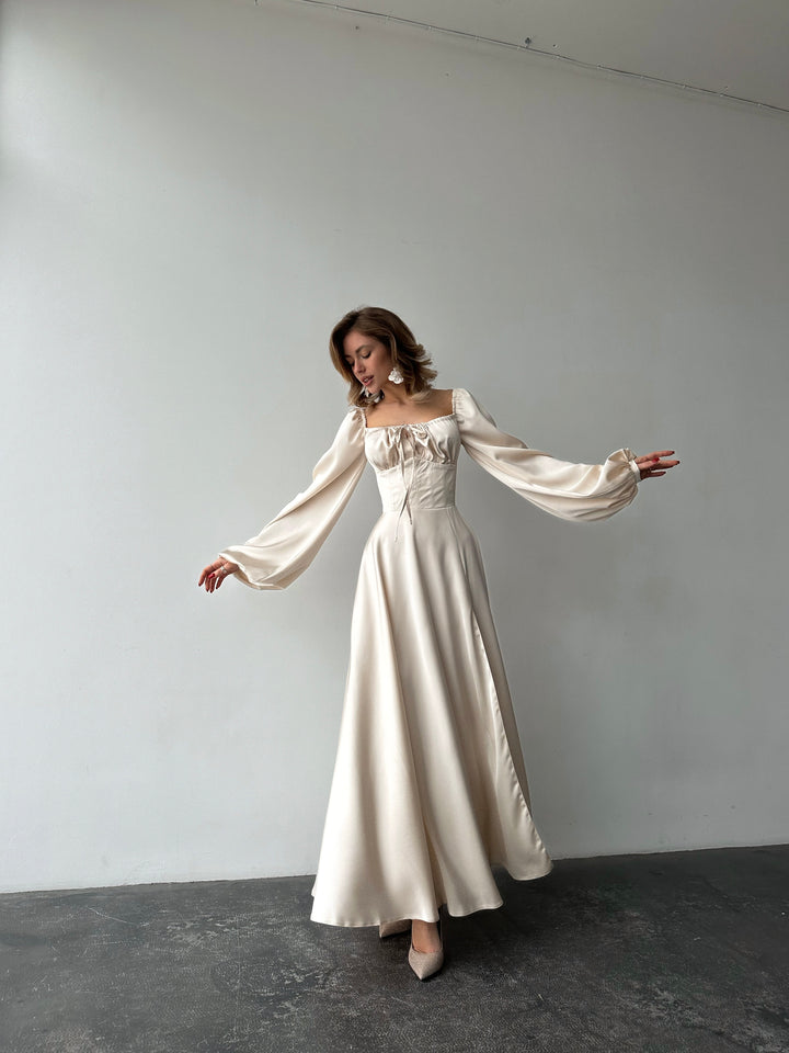 Ivory silk satin maxi dress — bishop sleeves gracefully extended, showing full volume and floor-length silhouette. Perfect for wedding guests, elopements, bridal editorial shoots, and formal gala evenings.
