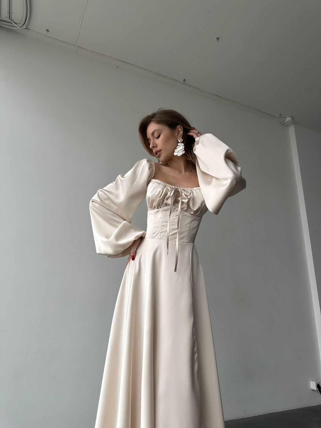Ivory silk satin maxi dress with lace-up corset bodice and bishop sleeves — confident front pose. Floor-length, sweetheart neckline. Perfect for civil ceremonies, elopements, rehearsal dinners, and black-tie galas.