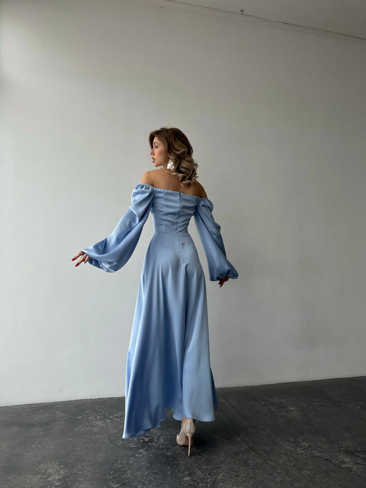 Romantic light blue satin maxi dress showcasing versatile bishop sleeves and a sweeping skirt with a thigh slit. Ideal for an elegant LA style evening out.