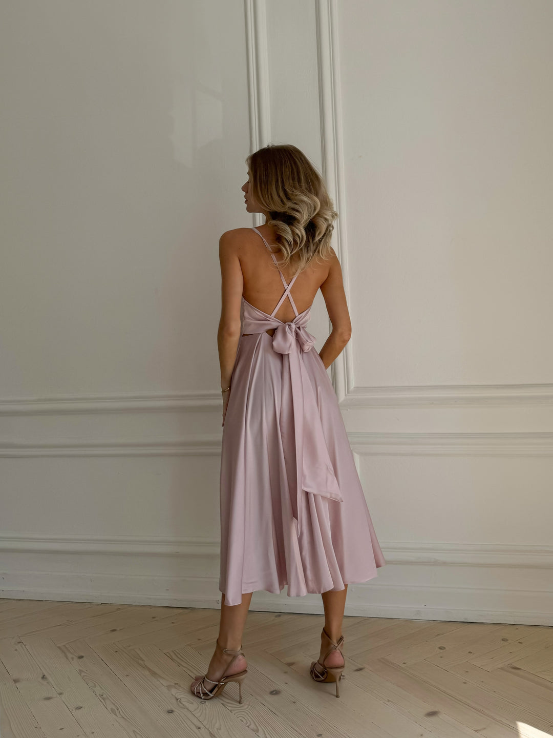Woman wearing light pink silk midi dress as bridesmaid at a spring wedding