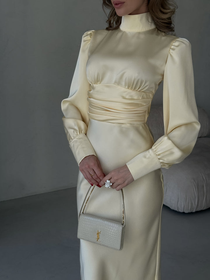 detail of the elegant long sleeves and smooth fabric drape on a butter yellow silk evening dress