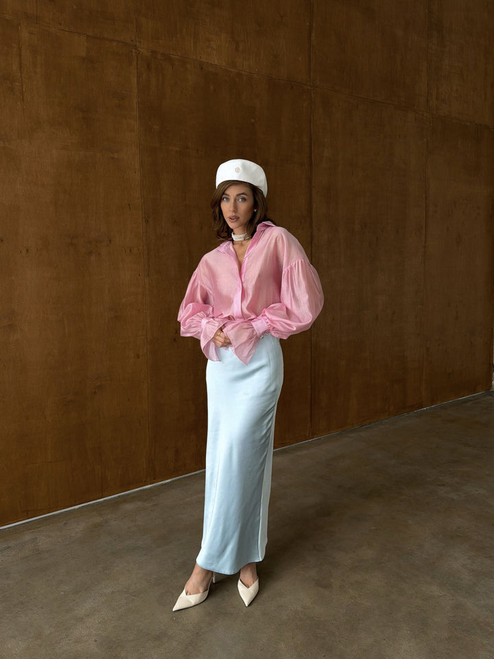 Side profile of the bubblegum pink sheer blouse showing straight hemline and airy sleeve volume