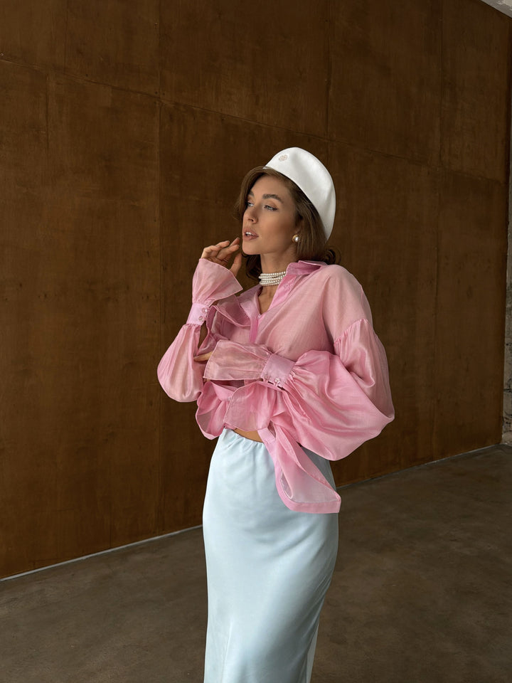 Side profile of model in pink sheer lyocell blouse showing straight hemline and airy sleeve volume