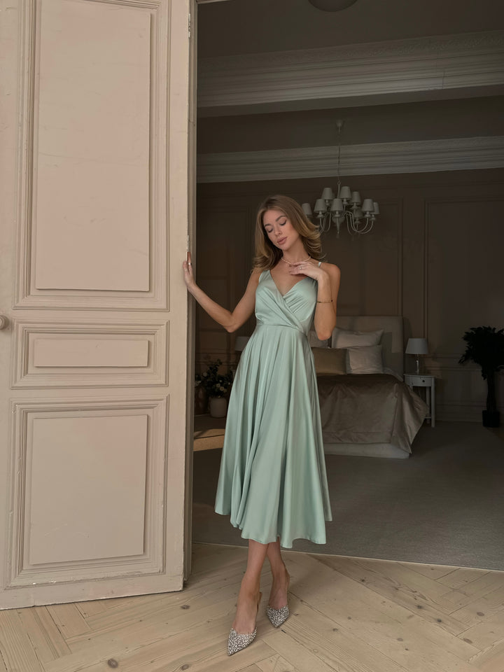 Woman wearing pistachio green silk midi dress as bridesmaid at garden wedding
