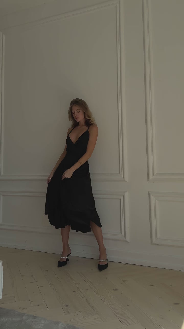 Black silk slip midi dress with deep V-neck and open back modelled in motion — EvolveUA