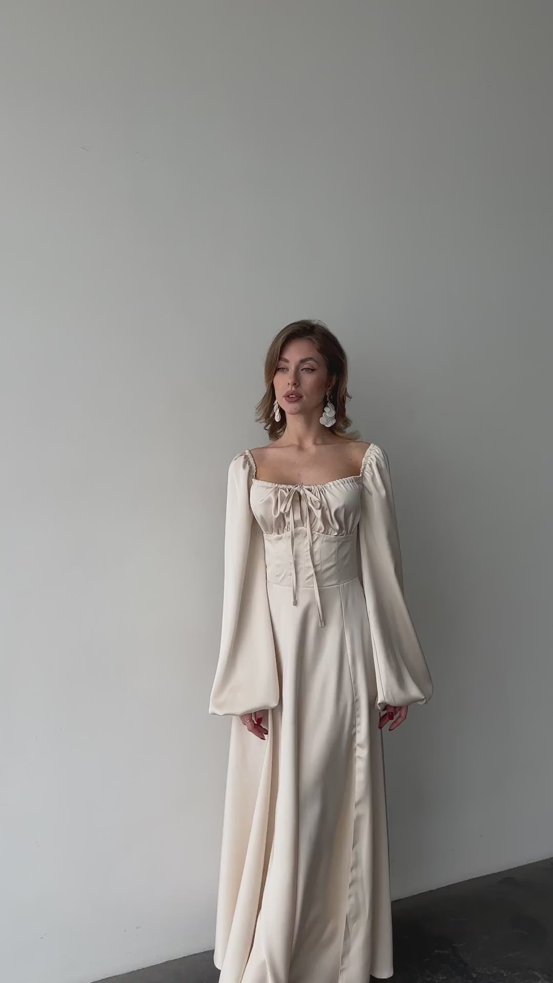 Ivory silk satin maxi dress with bishop sleeves in motion — floor-length silhouette with high slit and sweetheart neckline. Perfect for brides, elopements, civil weddings, and formal evening events.