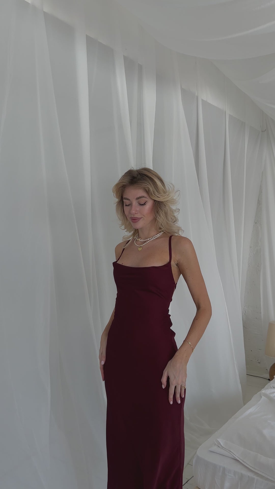 Video of a burgundy silk slip midi dress with lace up back demostrating the flow of the dress