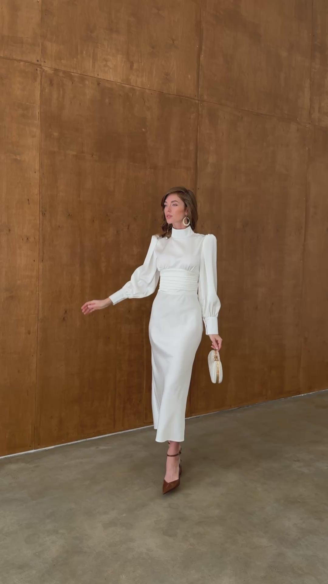 White satin midi dress with high neck, long sleeves and bow tie back modelled in motion — EvolveUA