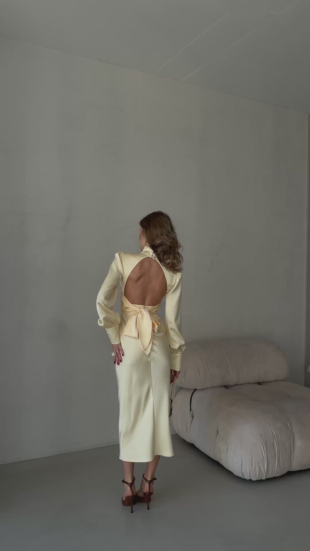 Close up of an open back butter yellow satin dress with a statement bow detail.