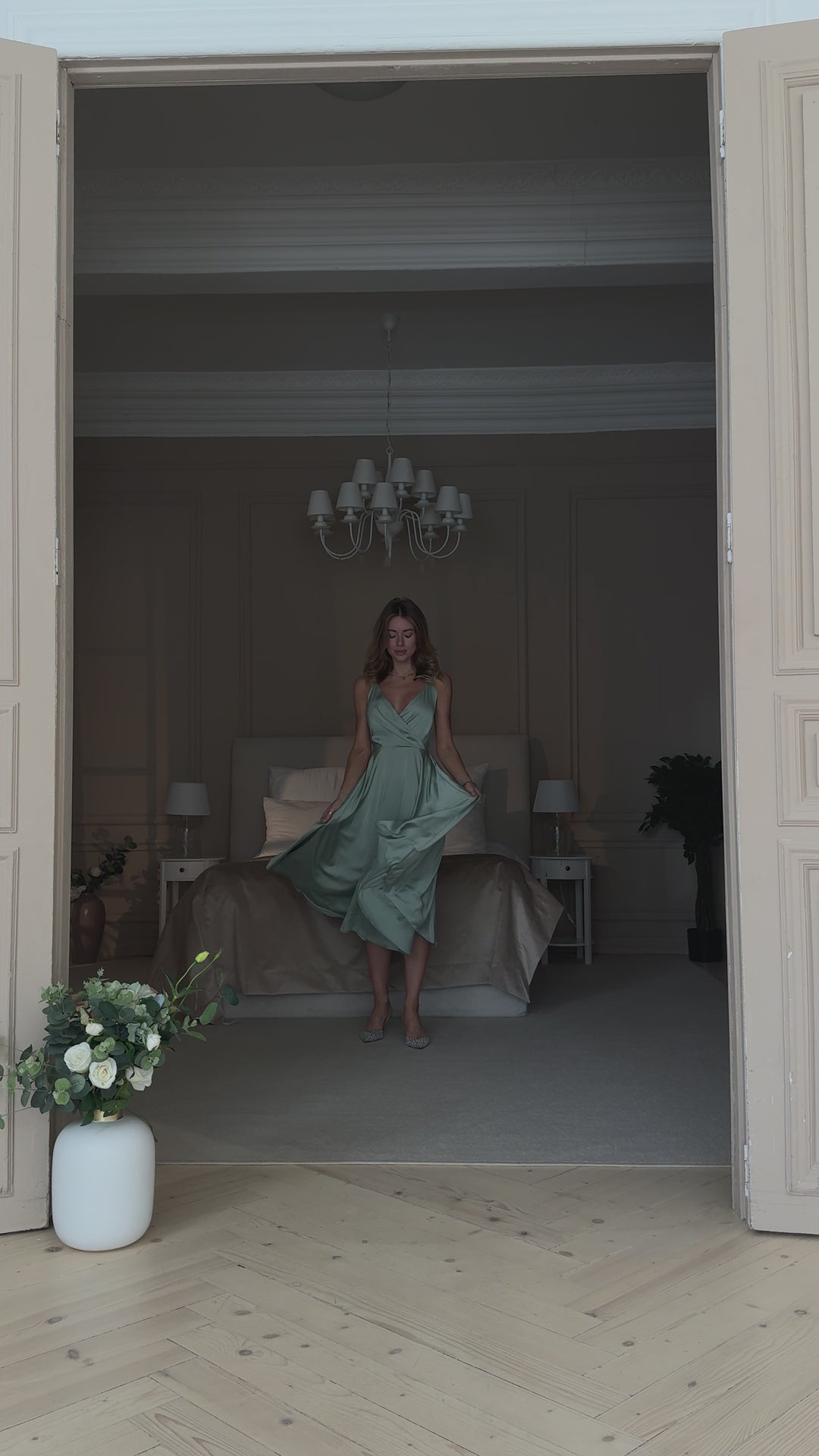 Pistachio green silk slip midi dress with deep V-neck and open back modelled in motion — EvolveUA
