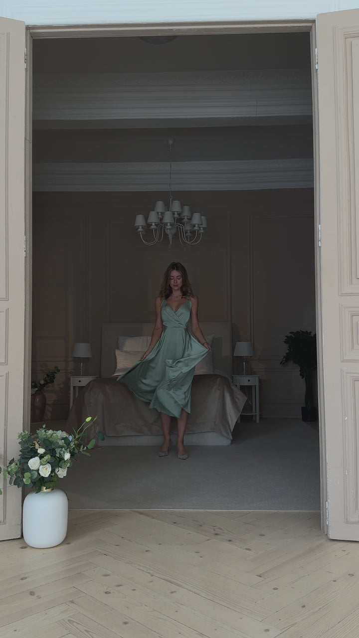Pistachio green silk slip midi dress with deep V-neck and open back modelled in motion — EvolveUA