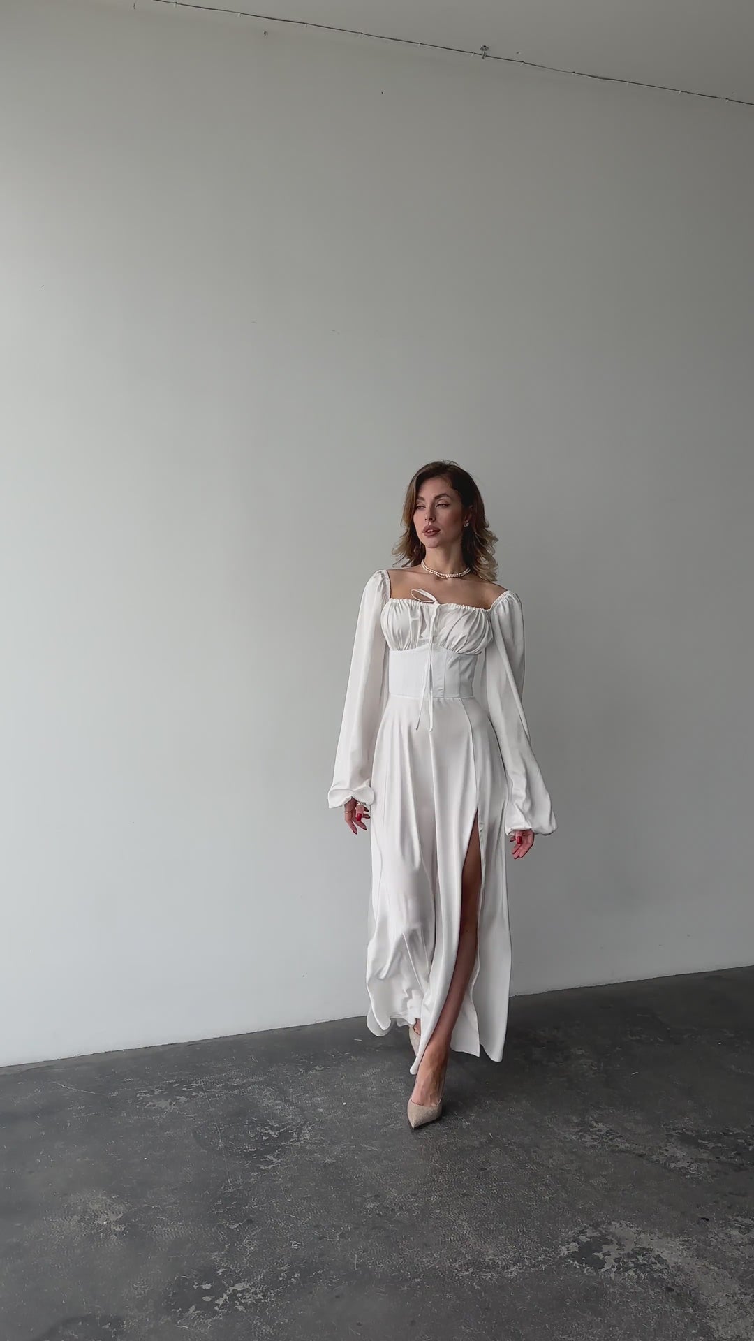 White silk satin maxi dress with bishop sleeves and high leg slit modelled in motion — EvolveUA