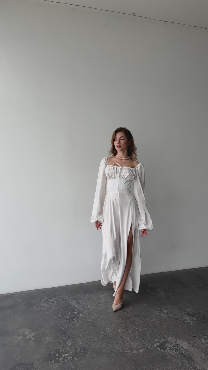 White silk satin maxi dress with bishop sleeves and high leg slit modelled in motion — EvolveUA