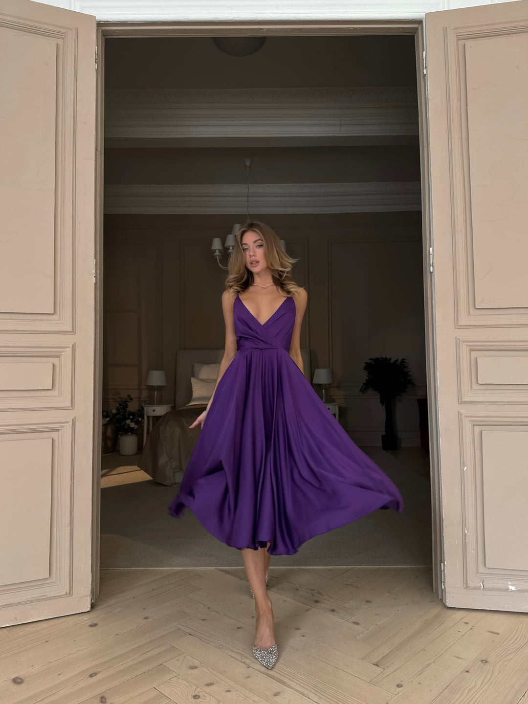 Woman wearing purple silk midi dress as bridesmaid at a formal wedding