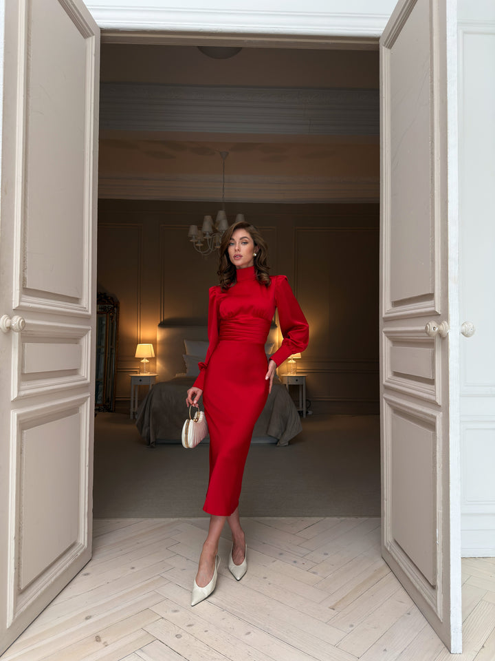 Red satin midi dress with high mock neck, puffed shoulders and long bishop sleeves, pleated waistband and fitted pencil skirt, full-length front view.
