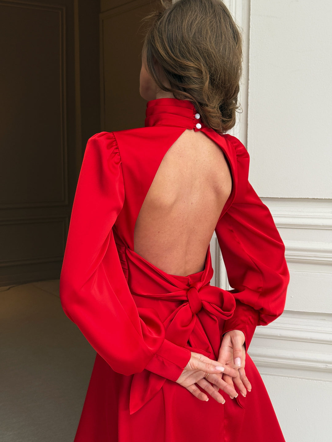 Red silk satin dress back detail: pleated high collar with two-button closure, open keyhole back, puff shoulders and large satin bow tied at the waist.
